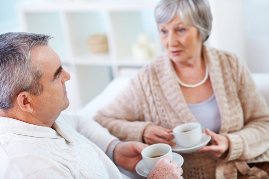 An elderly man and an elderly woman are talking about their apprehensions about senior living over a cup of coffee