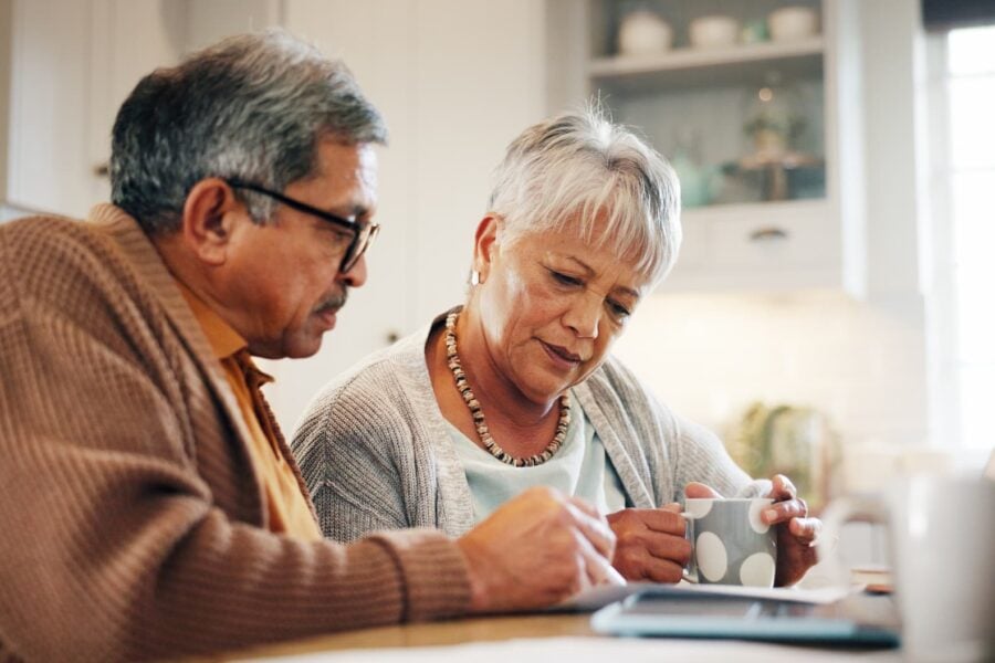 An elderly couple discussing and reviewing over their options on the computer, while discussing their plan