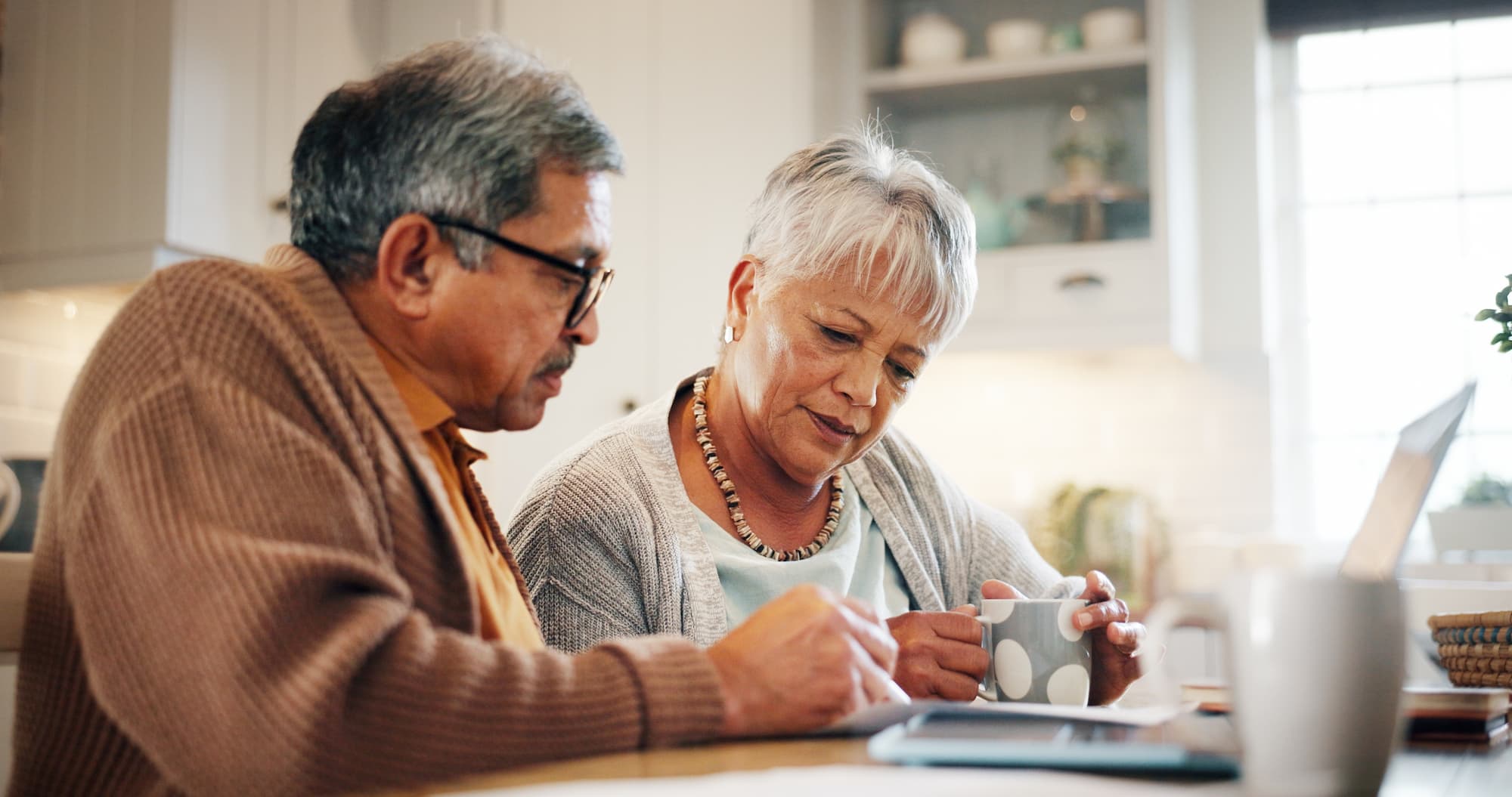 An elderly couple discussing and reviewing over their options on the computer, while discussing their plan